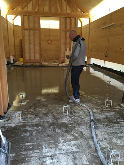 man pumping screed in wooden house